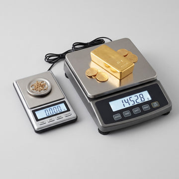 Digital gold weighing machine with LED display measuring jewellery on a stainless steel platform alongside a pocket scale