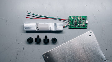 Disassembled weighing scale load cell, circuit board and stainless steel platform section on a workbench